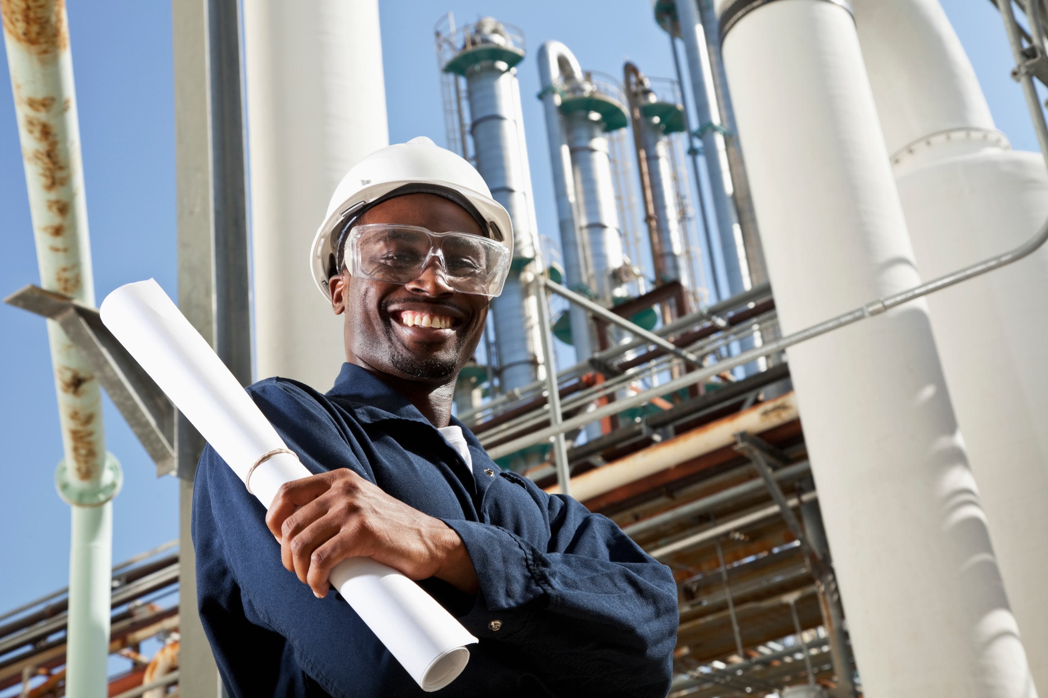Engineer holding technical drawings at a refinery site